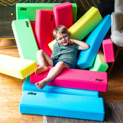 Child playing with colorful foam blocks on a wooden floor RIWI blocks